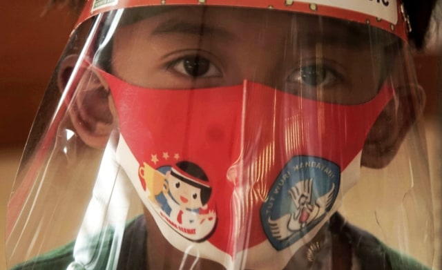 Seorang murid yang mengenakan pelindung wajah san masker saat mengikuti kelas tatap muka di sebuah taman kanak-kanak di Semarang, Jawa Tengah. Foto: Stringer/REUTERS