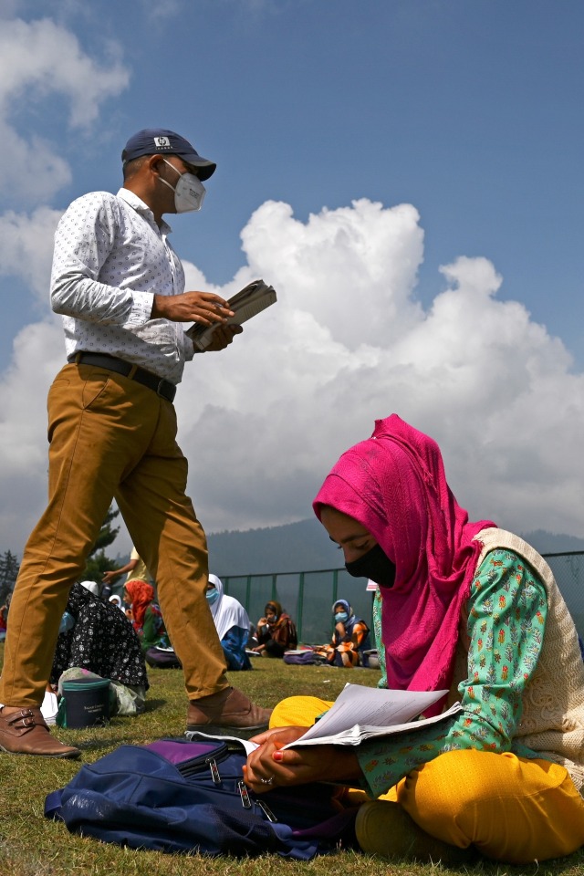 Seorang guru menerangkan pelajaran kepada siswa di sekolah terbuka mereka yang terletak di atas gunung di Doodhpathri, Kashmir, India. Foto: TAUSEEF MUSTAFA/AFP