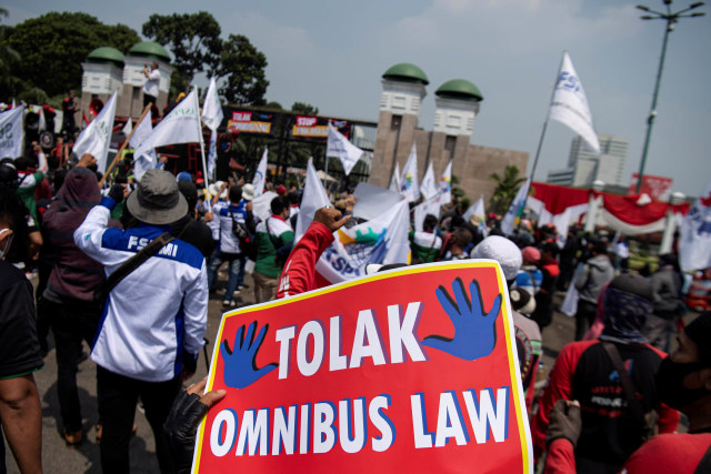 Sejumlah buruh membawa poster dan bendera saat melakukan aksi unjuk rasa di depan gedung DPR, Senayan, Jakarta. Foto: Sigid Kurniawan/Antara Foto