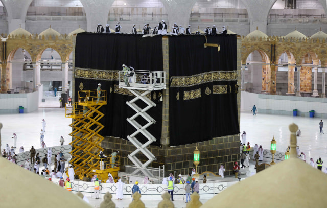 Proses penggantian Kiswah Ka'bah baru yang terbuat dari kain sutra hitam dan benang emas. Foto: AFP