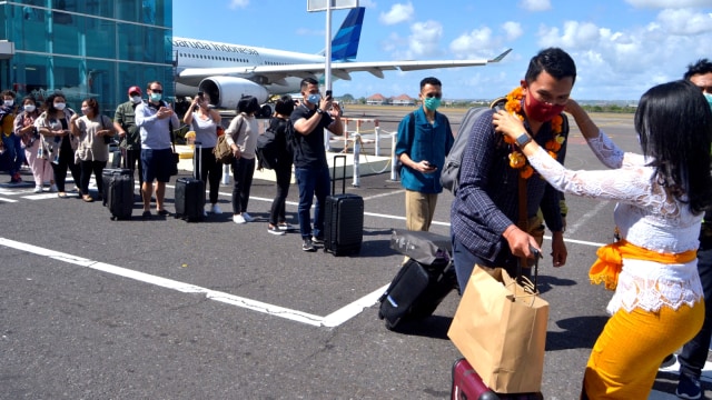 Petugas mengalungkan bunga untuk menyambut penumpang pesawat rute domestik yang tiba di Bandara Internasional I Gusti Ngurah Rai, Badung, Bali, Jumat (31/7). Foto: Fikri Yusuf/ANTARA FOTO
