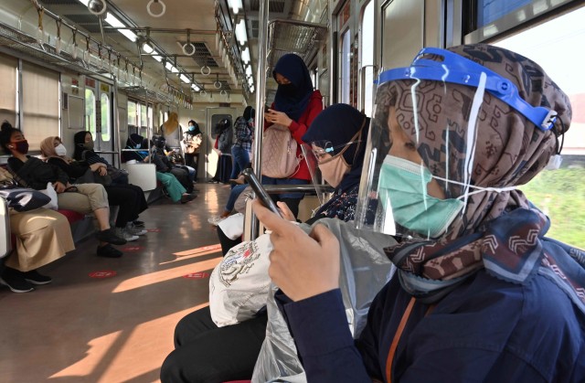 Warga menggunakan masker dan pelindung wajah saat menggunakan KRL dari stasiun Bogor. Foto: Adek Berry/AFP