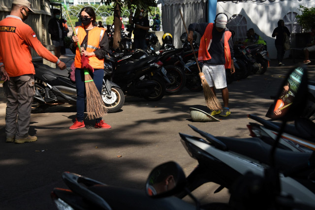 Pelanggar protokol kesehatan mendapatkan sanksi kerja sosial menyapu jalan di kawasan Bundaran HI, Jakarta, Minggu (26/7/2020). Foto: Indrianto Eko Suwarso/ANTARA FOTO