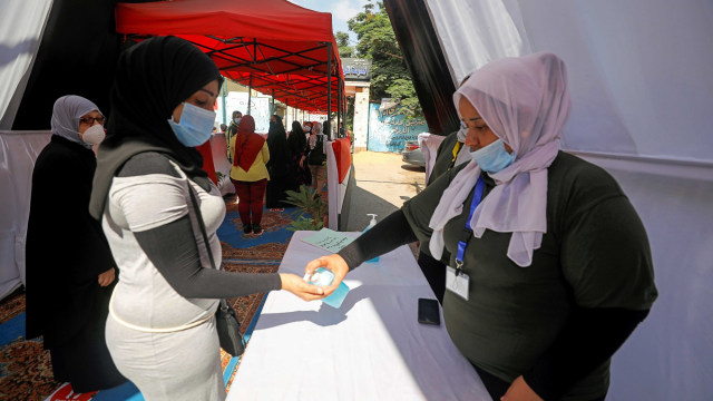 Panitia pemilu memberikan cairan pembersih tangan saat pemilihan Senat Mesir di Kairo, Mesir. Foto: MOHAMED ABD EL GHANY/REUTERS