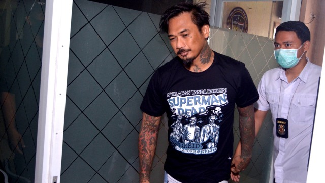 Drummer SID I Gede Ari Astina alias Jerinx (kiri) dikawal petugas disela menjalani pemeriksaan di Polda Bali, Denpasar, Bali, Selasa (18/8). Foto: Fikri Yusuf/ANTARA FOTO