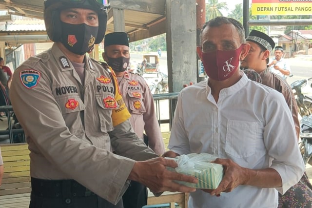 Anggota Polres Lhokseumawe, Aceh, saat membagikan nasi kotak gratis untuk jemaah salat Jumat sepulang dari masjid, Jumat (21/8). Foto: Dok. Polres Lhokseumawe