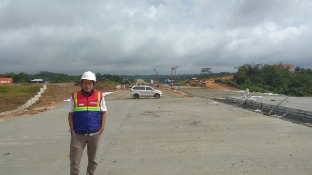 Penulis dengan latar belakang proyek konstruksi Tol Balsam