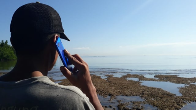 Muhammad Fadhel sedang menghubungi sahabatnya di Kendari, sementara ia sedang di Pulau Labengki kecil. Foto: Attamimi/kendarinesia.