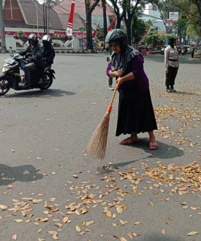 Salah satu warga yang mendapat hukuman sanksi sosial menyapu jalanan. Foto: Humas Pemkot Malang