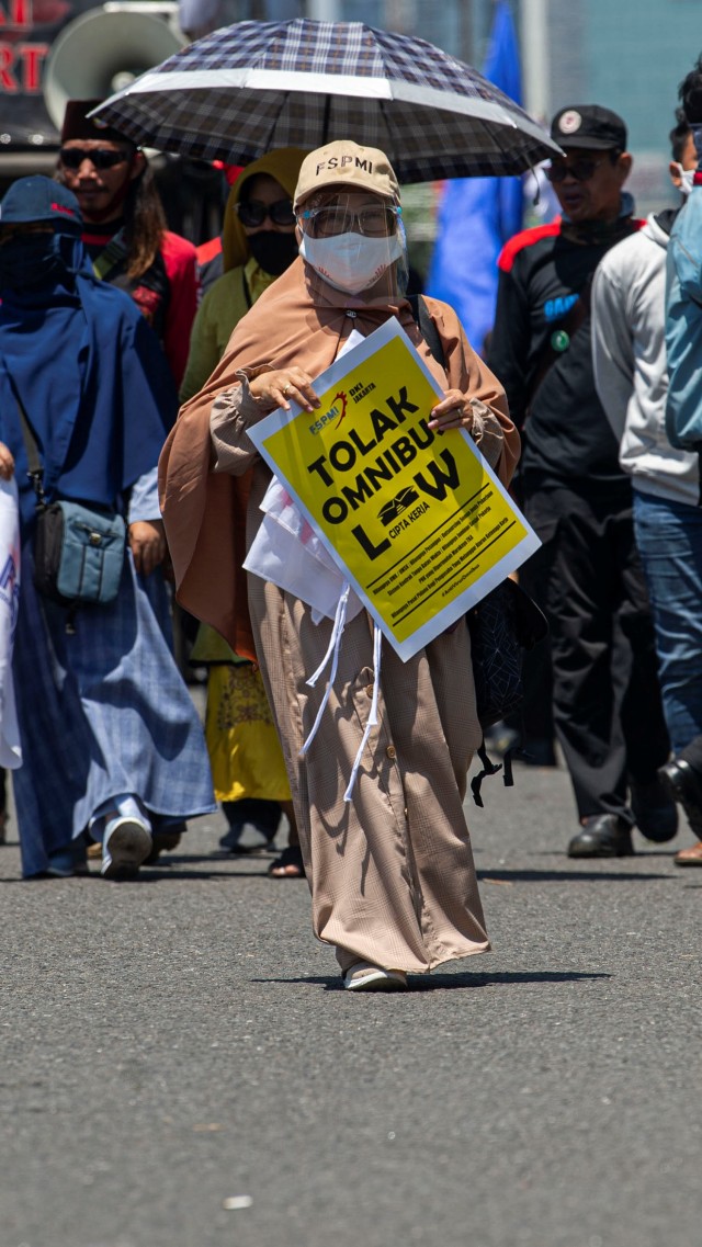 Seorang buruh membawa poster protes dalam aksi unjuk rasa di depan kompleks Parlemen, Senayan, Jakarta, Selasa (25/8). Foto: Aditya Pradana Putra/ANTARA FOTO