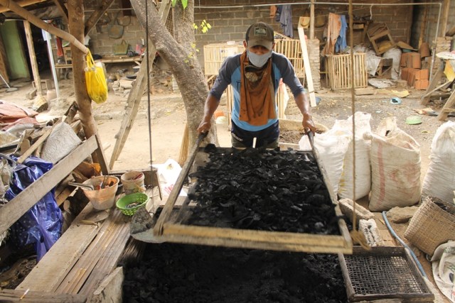 Muhaimin ketika mengayak arang di halaman belakang rumahnya. foto: rino hayyu setyo.