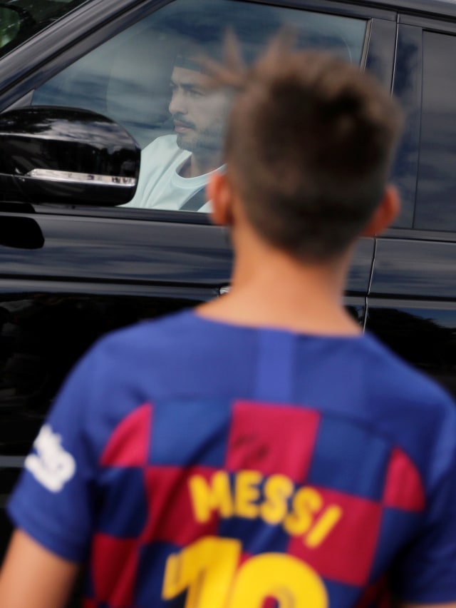 Seorang anak yang memakai baju Barcelona bertuliskan Lionel Messi berdiri di luar Ciutat Esportiva Joan Gamper Barcelona, Sant Joan Despi, Barcelona, Spanyol. Foto: Nacho Doce/REUTERS