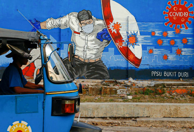 Sebuah bajaj melintasi mural yang berisi pesan waspada penyebaran virus Corona di kawasan Tebet, Jakarta. Foto: Ajeng Dinar Ulfiana/Reuters