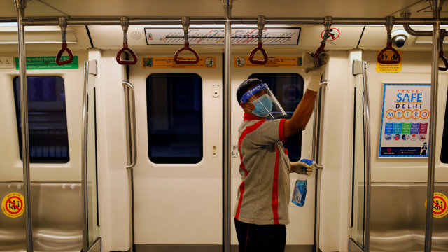 Seorang pekerja yang mengenakan pelindung wajah dan masker membersihkan gagang di dalam kereta di stasiun Metro Delhi, New Delhi, India, Kamis (3/9). Foto: ADNAN ABIDI/REUTERS