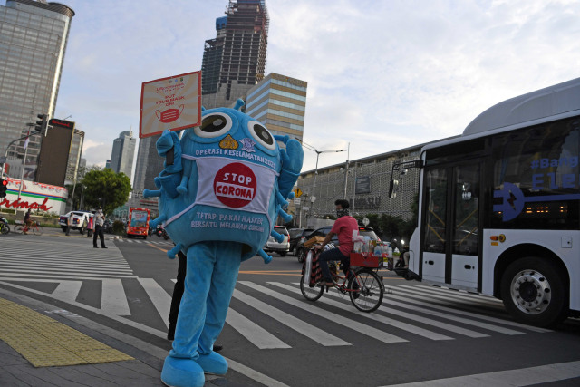 Petugas dengan kostum berbentuk virus corona membawa poster saat sosialisasi penggunaan masker di kawasan Sarinah, Jakarta. Foto: Wahyu Putro A/Antara Foto