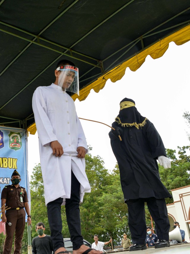 Algojo melakukan eksekusi hukuman cambuk terhadap salah seorang pasangan terpidana dalam kasus zina di Masjid Al Munawarah, Kota Jantho, Kabupaten Aceh Besar, Aceh, Jumat (4/9). Foto: Chaideer Mahyuddin/AFP