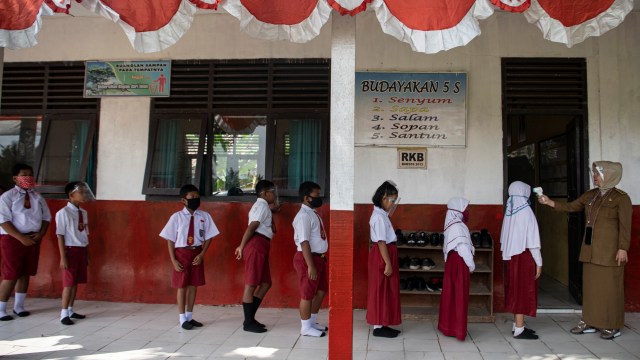 Guru memeriksa suhu tubuh siswanya sebelum mengikuti Kegiatan Belajar Mengajar (KBM) tatap muka di SD Negeri 26 Sukajadi, Banyuasin, Sumatera Selatan, Senin (7/9). Foto: Nova Wahyudi/ANTARA FOTO