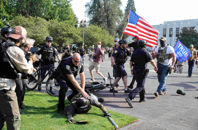 Petugas polisi membubarkan perkelahian antara pendukung Presiden AS Donald Trump dan pengunjuk rasa Black Lives Matter di luar gedung Oregon State Capitol di Salem, Oregon, Portland, Amerika Serikat. Foto: Carlos Barria/Reuters
