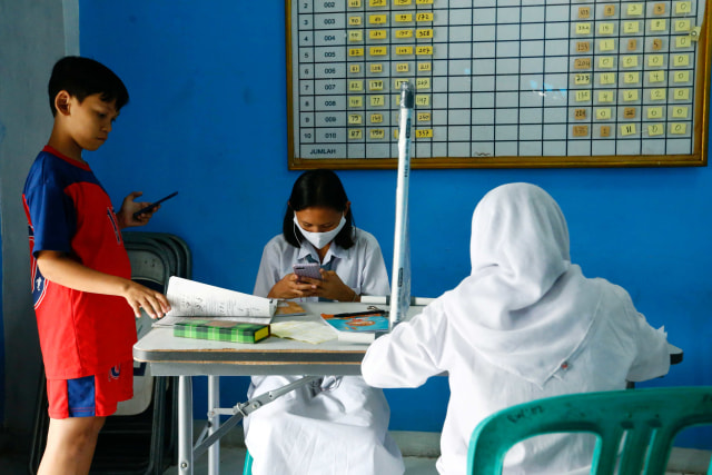 Siswa menerapkan sosial distancing saat belajar secara daring dengan akses internet gratis dari Pemprov DKI Jakarta di Kantor RW 02 Kampung Internet, Galur, Jakarta. Foto: Ajeng Dinar Ulfiana/Reuters