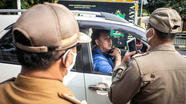 Petugas Satpol PP mengimbau kepada pengendara untuk menggunakan masker dengan baik dan benar dalam Operasi Yustisi Protokol COVID-19 di kawasan Pasar Jumat, Jakarta, Senin (14/9). Foto: Aprillio Akbar/ANTARA FOTO