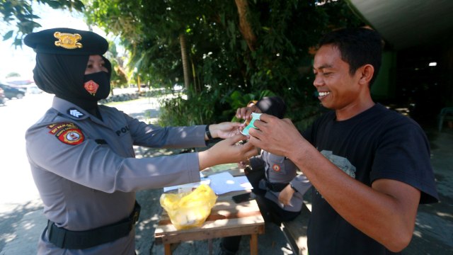 Petugas kepolisian memberikan masker kepada warga yang terjaring Operasi Yustisi penerapan protokol kesehatan di Jalan Jhon Aryo Katili di Kota Gorontalo, Gorontalo, Senin (14/9). Foto: Adiwinata Solihin/ANTARA FOTO