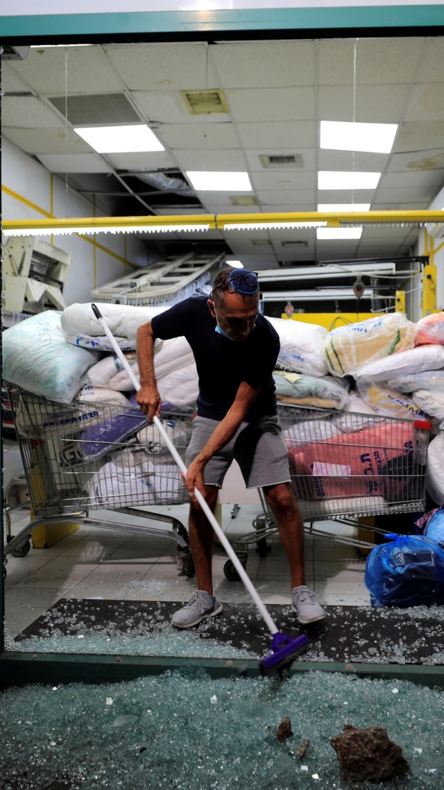 Seorang pria Israel membersihkan pecahan kaca di toko binatu setelah serangan roket yang ditembakkan dari Gaza di Ashdod, Israel, Selasa (15/9). Foto: Amir Cohen/REUTERS