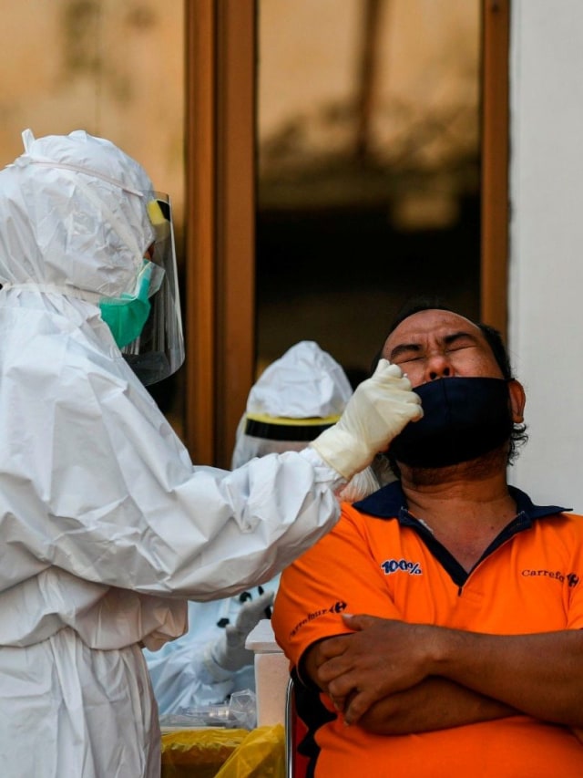 Seorang tenaga kesehatan yang mengenakan alat pelindung diri lengkap melakukan tes usap (swab test) COVID-19 pada warga di kawasan Pasar Keputran, Surabaya, Jawa Timur, Kamis (17/9). Foto: M Risyal Hidayat/Antara Foto
