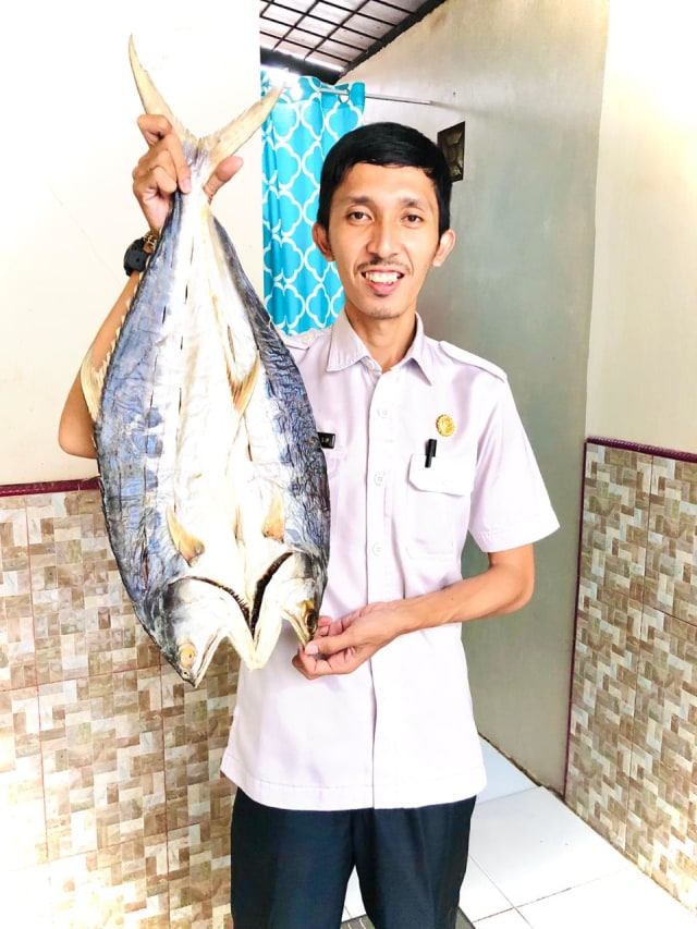 Rangga Lesmana, memperlihatkan ikan asin hasil produksi Desa Tanjung Putri. Foto Rangga.