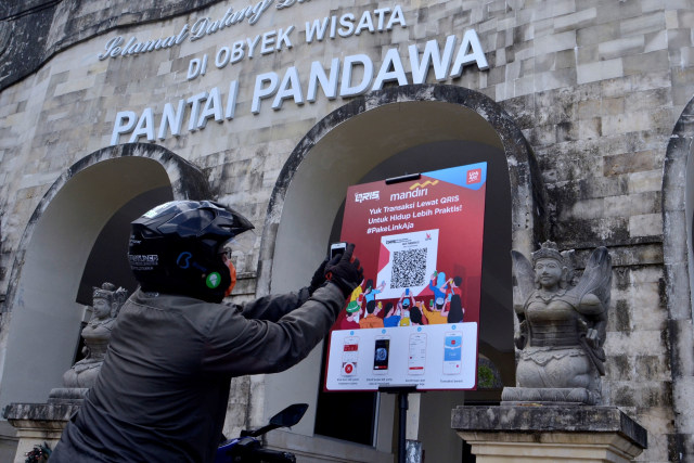 Pengunjung melakukan transaksi pembayaran berbasis digital dengan menggunakan Quick Response Code Indonesian Standard (QRIS) di Pantai Pandawa, Badung. Foto: Fikri Yusuf/ANTARA FOTO
