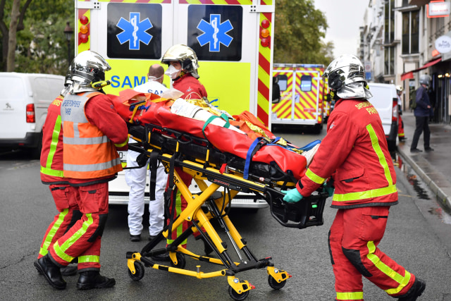 Petugas pemadam kebakaran Prancis mengevakuasi salah satu dari beberapa orang yang terluka akibat penyerangan di kantor majalah satir Prancis Charlie Hebdo di Paris, Prancis. Foto: Alain Jocard/AFP