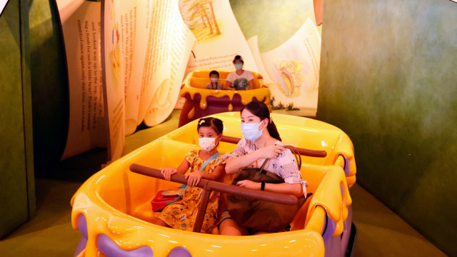 Pengunjung mengenakan masker menikmati wahana Disneyland Hong Kong yang kembali dibuka untuk umum di Hong Kong.  Foto: Tyrone Siu,REUTERS