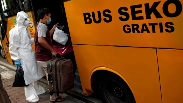 Petugas mengenakan alat pelindung diri (APD) membantu pasien corona naik bus untuk dipindahkan ke RS Darurat COVID-19 Wisma Atlet di Jakarta.  Foto: Willy Kurniawan/REUTERS