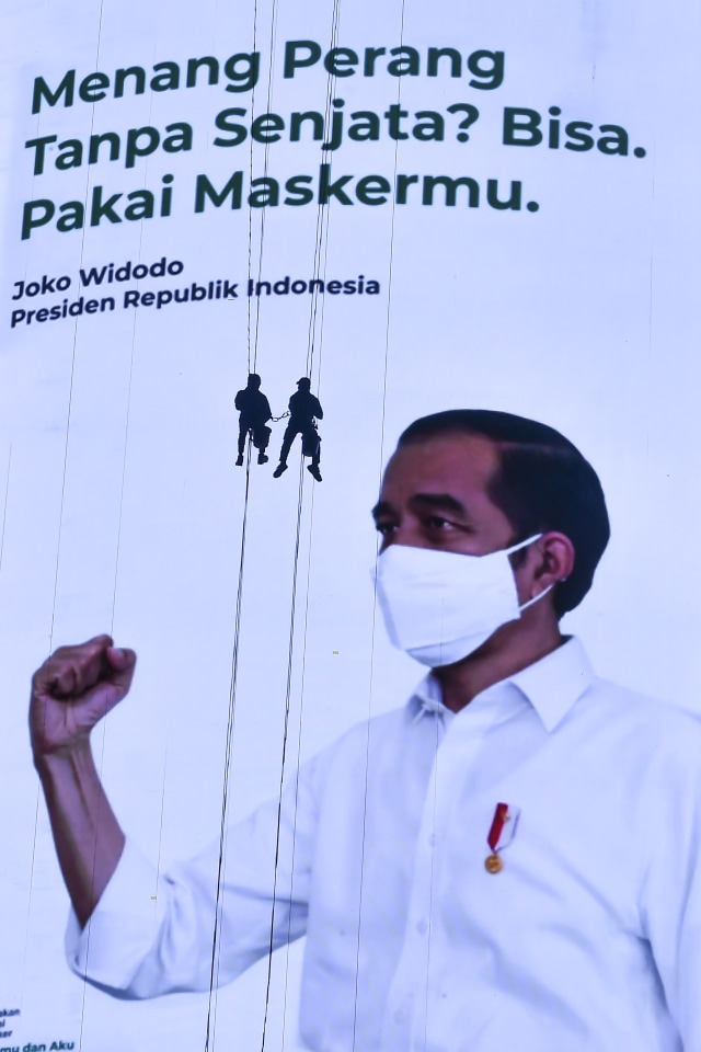 Pekerja membersihkan layar iklan pesan layanan masyarakat terkait penggunaan masker untuk penanganan COVID-19 di Jakarta, Minggu (27/9). Foto: Muhammad Adimaja/ANTARA FOTO
