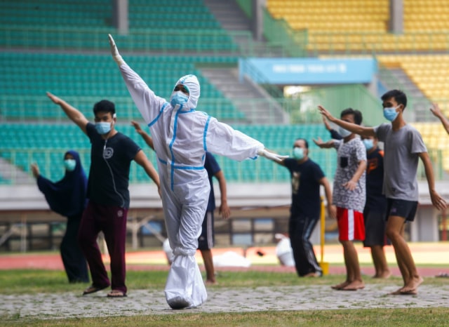Petugas medis menggunakan APD memimpin senam pagi bersama pasien COVID-19 berstatus Orang Tanpa Gejala (OTG) di Stadion Patriot Chandrabhaga, Bekasi, Jawa Barat, Senin (28/9). Foto: Ajeng Dinar Ulfiana/REUTERS