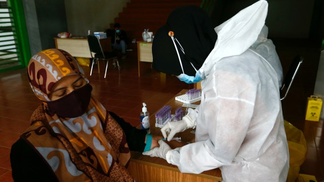 Petugas kesehatan yang mengenakan alat pelindung mengambil sampel darah untuk menguji seseorang untuk penyakit virus korona (COVID-19) di Stadion Patriot Chandrabhaga, Bekasi. Foto: AJENG DINAR ULFIANA/REUTERS