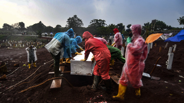 Petugas pemakaman memasukan jenazah ke dalam lubang di lokasi pemakaman COVID-19 TPU Pondok Ranggon, Jakarta, Jumat (2/10/2020). Foto: M. Adimaja/ANTARA FOTO