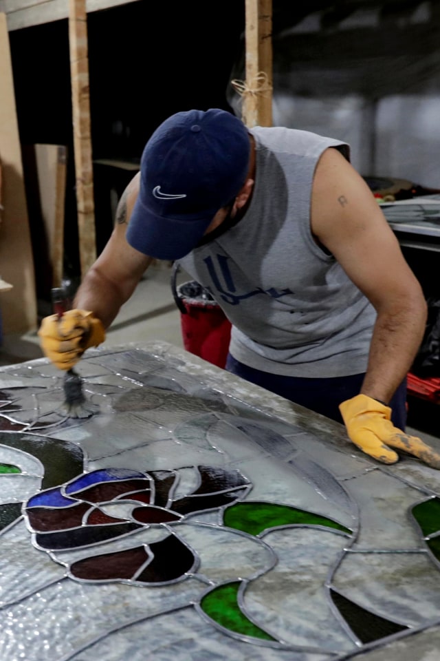 Seniman kaca patri Lebanon mengerjakan restorasi sebuah karya di bengkel bawah tanahnya di pinggiran ibu kota Beirut, Lebanon. Foto: ANWAR AMRO/AFP 