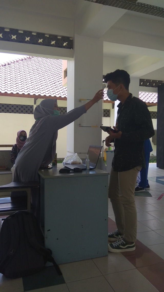 Pengecekan suhu tubuh menggunakan thermogun.