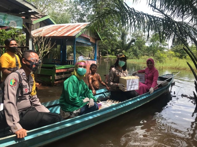 Ketua Bhayangkari Kobar Ny. Suci Andi Kirana bersama jajaran naik perahu getek mengantarkan bantuan untuk korban banjir di Kelurahan Baru. Dok. Polres Kobar