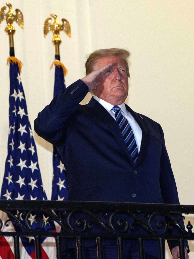 Presiden AS Donald Trump melihat keluar dari Truman Balcony saat  tiba di Gedung Putih sekembalinya dari Walter Reed Medical Center, tempat dia menjalani perawatan untuk Covid-19. Foto: Nicholas Kamm/ AFP