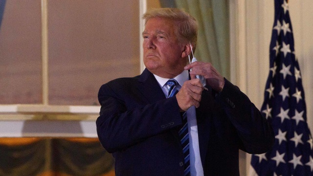 Presiden AS Donald Trump melepas masker saat tiba di Gedung Putih sekembalinya dari Walter Reed Medical Center, tempat dia menjalani perawatan untuk Covid-19. Foto: Nicholas Kamm/ AFP