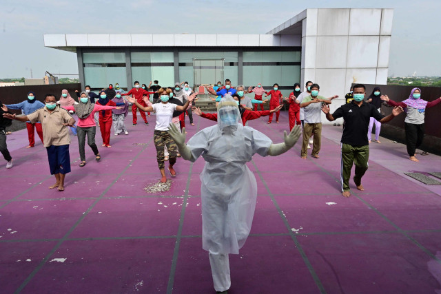 Seorang instruktur senam yang mengenakan APD memimpin senam pagi untuk pasien virus corona COVID-19 di sebuah hotel di Karawaci, Banten, Indonesia, Senin (5/10). Foto: Adek Berry/AFP