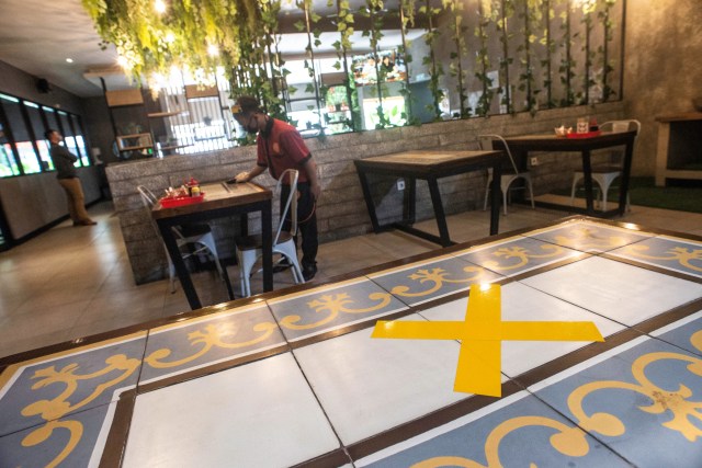 Pekerja memakai pelindung wajah dan masker membersihkan meja di restoran, Jakarta, Senin (12/10). Foto: Aprillio Akbar/ANTARA FOTO