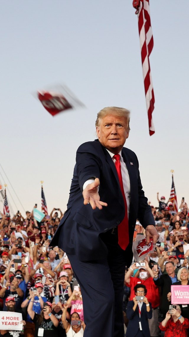 Presiden AS Donald Trump melempar masker saat kampanye, yang pertama sejak dirawat karena COVID-19, di Bandara Internasional Orlando Sanford di Sanford, Florida, AS, (12/10). Foto: Jonathan Ernst/REUTERS