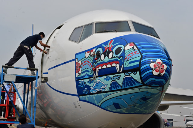 Pesawat Garuda Indonesia Boeing 373-800 NG dengan desain masker baru sebagai bagian dari kampanye penggunaan masker di tengah pandemi COVID-19. Foto: ADEK BERRY/AFP