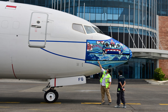 Pesawat Garuda Indonesia Boeing 373-800 NG dengan desain masker baru sebagai bagian dari kampanye penggunaan masker di tengah pandemi COVID-19. Foto: ADEK BERRY/AFP