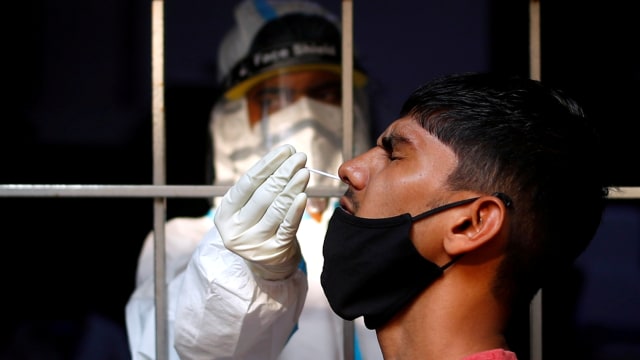 Seorang pria bereaksi saat petugas kesehatan mengambil sampel usap virus corona, di New Delhi, India, (17/10).  Foto: Adnan Abidi/REUTERS
