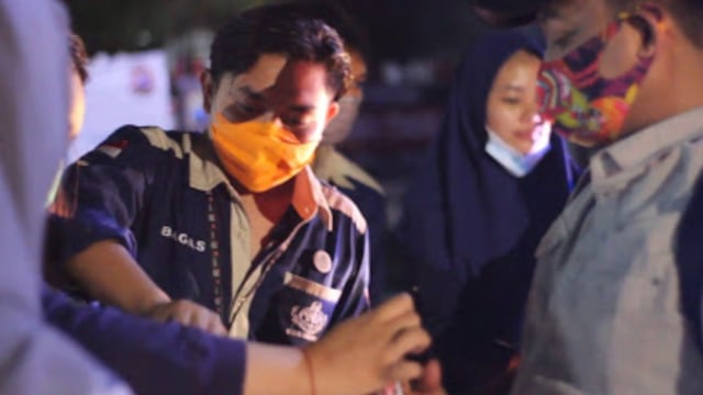 Salah satu anggota AMSA FK UMM sedang membagikan makanan