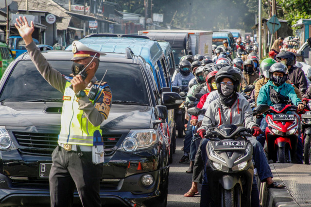 Polisi mengatur lalu lintas kendaraan yang memadati ruas jalan jalur Wisata Puncak, Kabupaten Bogor, Jawa Barat, Sabtu (31/10). Foto: Yulius Satria Wijaya/Antara Foto