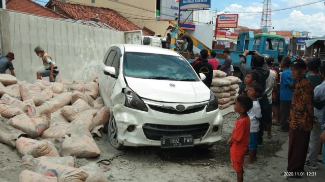 Warga Bumiayu melihat mobil dan truk semen yang terguling dan sedang dievakuasi.
